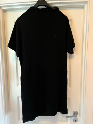 Svart klänning från g-star  - En stilren svart klänning  från G-Star RAW med diskret logga på bröstet. Klänningen har klassisk passform och korta ärmar. Perfekt basplagg till garderoben och tillverkad i mjuk bomull för skön känsla. Ryggen är ut av ett blankt material.