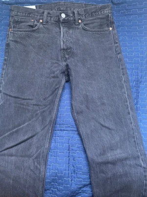 Grå raka jeans från Levi's - Säljer ett par klassiska grå jeans från H&M med rak passform. Jeansen har fem fickor, knappgylf och subtila kontrastsömmar. Tillverkade i slitstark denim som ger en tidlös look. Perfekta för dig som gillar en enkel och clean stil.