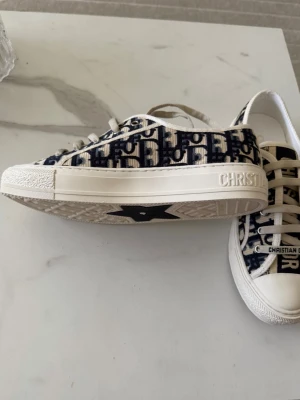 Dior Oblique sneakers i blått och vitt 38 - Säljer ett par snygga Dior Oblique sneakers i blått och vitt med klassiskt monogrammönster. Skorna har vita snören, gummisula med stjärndetalj undertill och tydlig Christian Dior-logga på sidan. Perfekta för dig som vill ha en exklusiv och trendig look.