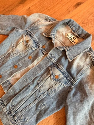 Ljusblå jeansjacka från Acne Studios - Säljer en klassisk  jeansjacka från Acne Studios. Jackan har långa ärmar, knappar framtill och två bröstfickor med lock. Storlek 34. Kanske lite mörkare färg i verkligheten 