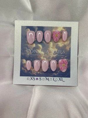 PinkLily (S);ExtraShortAlmond  - Säljer ett set handgjorda press-on naglar i en mjuk rosa nyans. Naglarna har en elegant extra kort almondform och två av naglarna är dekorerade med handgjord 3D-blommor och gulddetaljer för en extra söt touch. Perfekt för dig som vill ha unika och trendiga naglar.S: 15 mm, 11,5 mm, 12 mm, 11 mm, 9 mm 