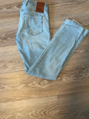 Ljusblå skinny jeans Replay - Säljer ett par ljusblå skinny jeans från Replay med klassisk femficksmodell och läderpatch bak i midjan. Jeansen har en smal passform och är tillverkade i stretchigt denimtyg för extra komfort. Perfekta till en avslappnad look.