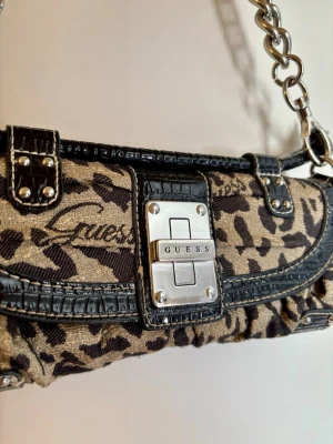 Vintage handväska från Guess - Säljer denna otroligt fina och originella vintage GUESS väskan då den tyvärr bara har hängt i garderoben. Jag köpte den på second hand förra året för ca 1,500kr. Är i väldigt bra skick och hoppas den får kommas till använding igen! 🖤🐆🤎