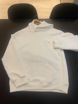 Vit hoodie  - Säljer en stilren vit hoodie från.  Hoodien har klassisk känguruficka, ribbade muddar och mjukt material som känns lyxigt. Perfekt för dig som gillar exklusiva streetwear-plagg.