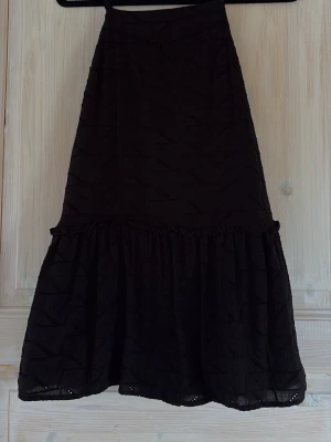 Svart Zara klänning  - Svart klänning från Zara med volangkant och broderade detaljer. Låg i ryggen och ett lätt, luftigt material som passar perfekt för varma dagar. Snyggt mönster i tyget ger en cool look. Storlek xs, säljs ej i butik längre, nytt skick!