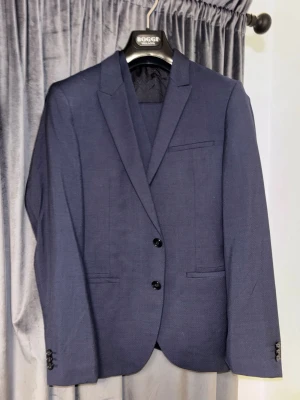 Hugo boss mörkblå kostym, Boggi Milano - Mörkblå Hugo Boss kostym. Köpt för 6500kr. Använts 3 gånger. Full kostym (kavaj, väst, byxor). 