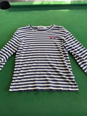 Randig långärmad topp Comme des Garçons - Säljer en randig långärmad tröja från Comme des Garçons Play med marinblå och vita ränder. Säljer då den inte passar. Hör gärna av er vid fler frågor
