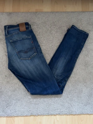 Replay anbass w32/l34 - Säljer ett par blå jeans från replay med snyggt slitna detaljer och broderad bakficka. Klassisk femficksmodell med brunt läderpatch i midjan och raka ben. Jeansen är i ett mjukt denimtyg. Hör av er vid några som helst frågor priset går att diskuteras 👍