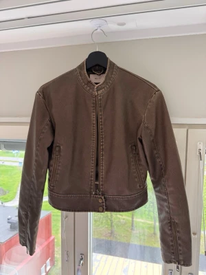 Nelly skinnjacka i vintagebrun - Trendig skinnjacka från Nelly i mörkbrun/vintageinspirerad nyans. Croppad modell med praktiska fickor och detaljer vid ärmslut. Fint skick🤎