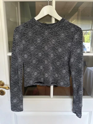Glittrig croppad topp  - Svart långärmad croppad topp från H&M i svart och silverglittrigt mönster. Mjukt och stretchigt material som sitter bekvämt. Perfekt som festblus eller bara när man vill va lite extra snygg💫