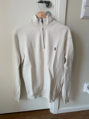 Vit halvzip Ralph Lauren - Klassisk vit tröja från Ralph Lauren med halv dragkedja och hög krage. Passar S/M