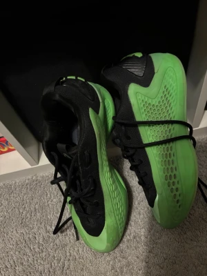 Svart och grön sneaker från Nike - Säljer ett par snygga sneakers från Nike i svart och grönt. Skorna har en sportig design med meshdetaljer på ovandelen och en robust sula. De har svarta skosnören och en cool struktur på sidan. Perfekta för dig som gillar streetwear och vill sticka ut.