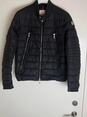 Moncler Amiot Down Biker Jacket - Säljer en Moncler Amiot i svart. Stilren biker-modell med slim fit, sitter riktigt snyggt. Bra skick 8/10 bortsett från att det saknas cartoon.  Finns ute på Monclers hemsida för 16 150 kr