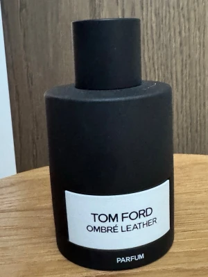 Tom Ford Ombré Leather Parfum unisex helt ny  - Tom Ford Ombré Leather Parfum i en stilren, matt svart flaska med rund form och vit etikett. Flaskan har minimalistisk design och känns lyxig, perfekt för dig som gillar exklusiva dofter och snygga parfymflaskor i badrumshyllan.