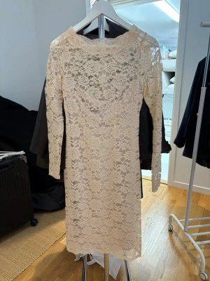 Ljus spetsklänning med lång ärm - Elegant ljus spetsklänning med långärmad design och vackert blommönster. Klänningen har en rak passform och hög halsringning, perfekt för dig som gillar romantisk stil. Materialet är mjukt och följsamt, vilket ger en bekväm känsla. Original pris var 3000:-, pris kan diskuteras! 