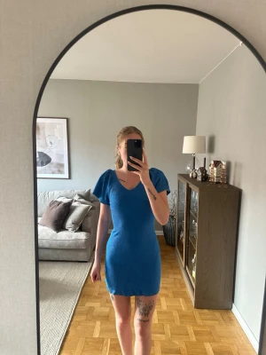 Blå ribbad kortklänning från only  - Snygg blå kortklänning från only som är  ribbad och v-ringning. Klänningen har lite puffiga kortärmar och en öppen rygg med knytband. Använd ett fåtal gånger. 