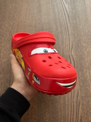Lightning McQueen Crocs - Säljer ett par helt nya Lightning McQueen Crocs i storlek 38–39. Aldrig använda.  Supercoola och populära skor utan blinkande ljus. Perfekta för både vardag och som en rolig detalj i outfiten.  - Storlek: 38–39   - Skick: Helt nya   - Färg: Röd med Lightning McQueen-design    Säljes eftersom de inte kommer till användning.  💬 Hör av dig vid frågor!   📦 Snabb frakt!