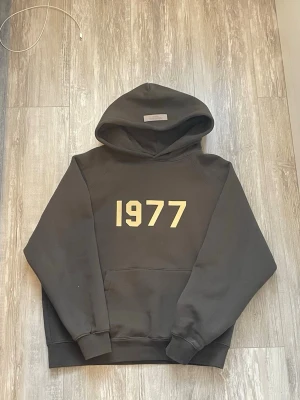 Essentials Fear of God "1977" Hoodie - Säljer nu min Essentials 1977 hoodie i en sjukt snygg mörkgrå/tvättad svart färg. Den perfekta hoodien med den klassiska boxiga passformen som sitter helt rätt. Kraftigt tyg av hög kvalitet som håller formen. 