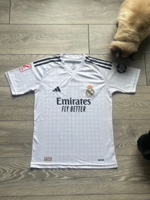 Real Madrid Hemmatröja 24/25 – Kylian Mbappé #9 – Storlek XS - Säkra säsongens mest eftertraktade tröja! Officiell Real Madrid-hemmatröja för säsongen 2024/25 med klubbens nya superstjärna Kylian Mbappé på ryggen. • Lag: Real Madrid (La Liga) • Spelare: Kylian Mbappé #9 • Säsong: 2024/2025 • Storlek: XS • Färg: Klassisk vit med svarta detaljer • Skick: Mycket fint skick, som ny. • Detaljer: Inkluderar de officiella märkena och det nya typsnittet för namntrycket. En fantastisk tröja för både samlare och supportrar som vill fira Mbappés ankomst.