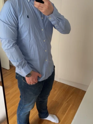 Nyskick! Ralph Lauren Skjorta  - Säljer nu min riktigt schyssta Ralph Lauren skjorta! Den är i ny skick, endast använd 1-2 gånger.                                                            ❗️Väldigt ”andande” och mjukt material, så perfekt för våren/sommaren!❗️.               Storleken är M, och är rätt true to size.                    ✅Modellen på bilden är ca 178 och väger 84kg.        ✅Skjortan är i nyskick, och självklart äkta!