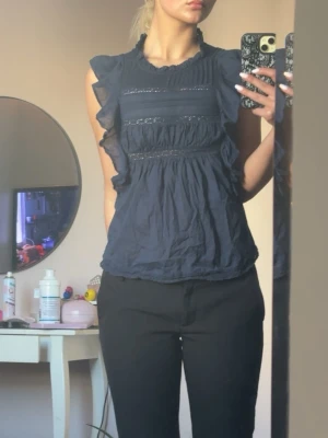 Mörkblå volangblus med spetsdetaljer - Snygg mörkblå blus med volanger längs axlarna och spetsdetaljer framtill. Stockholmsstil och perfekt för sommaren💕