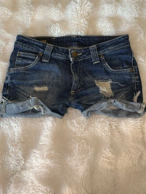 Lågmidjade Lee jeansshorts - Säljer ett par blå denimshorts från Lee. 37 cm i midjan och längd: 26 cm. Dom sitter skit snyggt på säljer tyvärr för att dom är för små:(