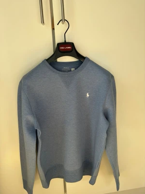 Polo Ralph Lauren: Premium Sweatshirt - Klassisk blå sweatshirt från Polo Ralph Lauren med rund halsringning och den ikoniska vita logon broderad på bröstet. Tröjan har ribbade muddar vid ärmslut och nederkant. Perfekt för en avslappnad och stilren look.      🎉699 pris då tröjan är köpt på Boozt för 2195 och precis som ny! 🎉För mer info skriv dm!