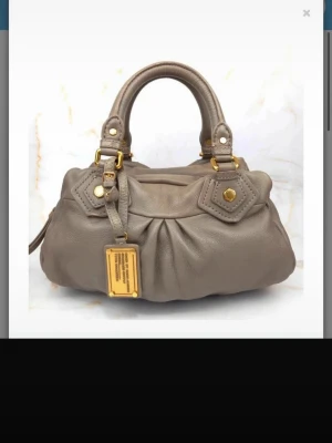 Marc Jacobs classic Q beige - Säljer en vintage Marc Jacobs classic Q läderväska med guldiga detaljer. Väskan är i fint skick både invandigt och utvändigt. Färgen är lite svår att definiera men skulle säga att det är blanding mellan beige/grå. Axelrem skickas meds Hör av dig vid några funderingar!