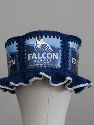 Virkad ölhatt Falcon öl - Unik virkad ölhatt med Falcon.  Virkad i 100% bomull. Passar upp till ca 60cm.  Vissa burkar kan ha mindre repor eller bucklor, vilket tyvärr kan uppstå under tillverkningen av hattarna. Insidan av burkarna slipas efter hålen tagits för att undvika vassa kanter. Därför kan det ibland finnas lite slipmärken, men det är inget som stör eftersom det är på insidan av hattarna.  Färger kan variera något beroende på skärminställningar.