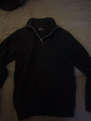 Svart stickad tröja med halvzip - Mörk stickad tröja med halv dragkedja och hög krage. Tröjan är storlek S men passar även bra på XS. Tröjan har en enkel, stilren design. Några funderingar är det bara att höra av sig 