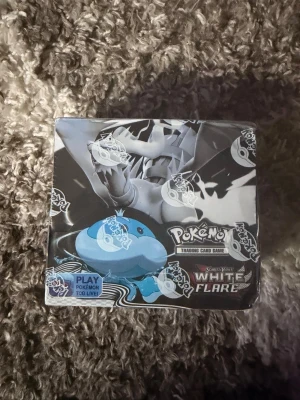 Pokémon Scarlet & Violet White Flare Box - Säljer en Pokémon Scarlet & Violet White Flare booster box. Förpackningen är svart och vit med motiv av olika Pokémon och loggan för Pokémon Trading Card Game. Perfekt för samlare eller dig som vill bygga din kortsamling. Materialet är kartong och plast.