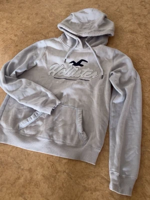 Hollister Hoodie - ⚠️Är storlek M på lappen men sitter som XS⚠️ Riktigt snygg grå hoodie från Hollister som tyvärr är för liten för mig, jag är ca 180. Inga defekter finns. Skriv vid funderingar!🔥