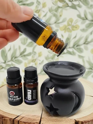 Aromalampa keramik svart - Aromalampa i svart keramik. Lampan har utskurna stjärnformade hål på sidorna och en skål upptill för doftolja eller vax. Avsedd för användning med värmeljus som placeras i öppningen framtill. Passar för spridning av doftoljor i hemmet eller som enkel dekoration i inredningen. 7 cm hög. Bredd 6 cm. Handgjord.