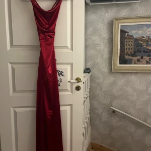 Röd långklänning med slits - Röd långklänning i satinliknande material med smala axelband. Klänningen har en hög slits framtill. Den är endast testad!✨ Men perfekt balklänning! Köpt från SHEIN men har tjockt tyg med känsla av kvalite.
