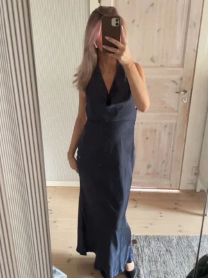 Marinblå balklänning med öppen rygg - Pris kan diskuteras vid snabb affär! Säljer en elegant marinblå långklänning i ett glansigt material med djup v-ringning och öppen rygg. Klänningen har en figurnära passform och knyt i nacken för en snygg siluett. Perfekt för dig som vill sticka ut på nästa event!