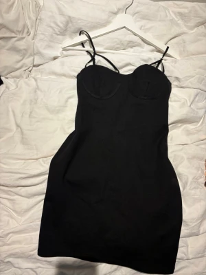 Svart kort klänning  - En svart kort klänning med detaljer vid bysten. Den sitter tight och formande, den är från Zara och är i ett lite tjockare material. 