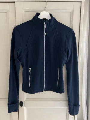 Lululemon define jacket i mörkblå - Lululemon define jacket i mörkblå med silvriga detaljer. Jackan är figursydd och perfekt för träning! Jackan är använd fåtal gånger och i väldigt fint skick. 
