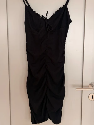 Svart ”scrunchad” klänning  - Jättefin svart scrunchad klänning som man både kan bära som lång eller ganska kort. Jättebra för sommaren då tyget är ganska tunnt (ej genomskinligt). Tror den är köpt från H&M för några år sedan, men är knappt använd.