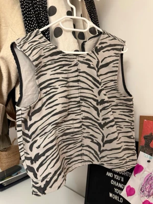 Zebramönstrad väst i bomull - Snygg zebramönstrad väst i svart och beige med dragkedja bak. Västen har en rak passform och är tillverkad i ett mjukt bomullstyg. Perfekt för att addera lite edge till din outfit.