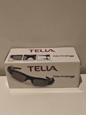 Smart Video Recording Sunglasses med MP3 och Kamera - Smarta glasögon från Telia med inbyggd videokamera och MP3-spelare. Svart sportig design med polariserade linser och användarvänliga knappar. Stöd för flera musikformat, 2GB minne för upp till 1,5 timmes videoinspelning och plats för microSD-kort. Passar både killar och tjejer. Kopplas till dator med inkluderad utrustning.