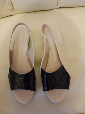 Beige sandaler med svart krokopräglad detalj stl 40 - Snygga sandaler i beige med öppen tå och bred svart krokopräglad rem över foten. Slingback-modell med låg klack och stilren design. Perfekta för dig som gillar en modern och trendig look. Materialet ser ut att vara konstläder.stl 40