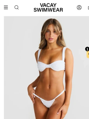 Vit bikini från Vacay Swimwear - Stilren underbar vit bikini från Vacay Swimwear med breda axelband och bygel i toppen. Underdelen har hög midja och smala sidor. Perfekt för strandhäng och poolparty. HELT NY MED ALLA LAPPAR KVAR (beställde flera storlekar men missade att skicka tillbaka). Nypris ca 1000kr