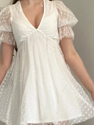 Vit kort klänning med puffärmar - Söt vit prickig kortklänning med v-ringning och puffiga, genomskinliga kortärmar från Gina tricot. Som jag bara använt 2 gånger. Skriv ifall att ni har några frågor om klänningen!!!