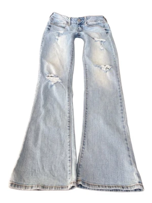 Ljusblåa superlågmidjade bootcut jeans med slitningar - Så sjukt snygga vintage superlågmidjade jeans med slitningar från American eagles! Extremt eftertraktade och trendar på Pinterest💓 Midjemått rakt över: 39 cm , Innebenslängd: 82 cm