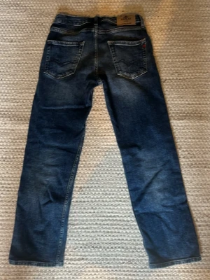 Mörkblå Replay Thad Jeans - Säljer ett par klassiska blå jeans från Replay med raka ben och femficksmodell. Perfekta för en avslappnad och tidlös stil.
