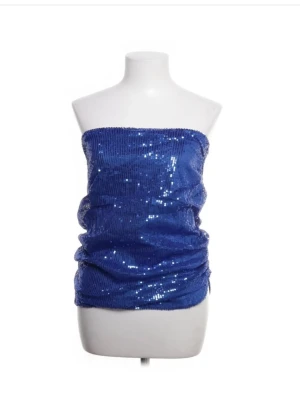 Tubtopp - Snygg blå tubtopp täckt med glittriga paljetter. Toppen är axelbandslös och har en bandeauformad passform som sitter tight runt överkroppen. Perfekt för dig som vill sticka ut och glänsa lite extra.