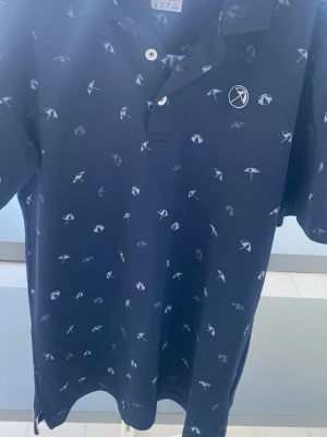 Mörkblå piké från Puma med parasoll - Snygg mörkblå pikétröja från Puma x Arnold Palmer. Mycket skön och stilig piké!