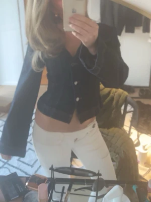 Mörkblå jeansjacka från Gina Tricot - Snygg mörkblå jeansjacka från Gina Tricot med figurnära passform och vida ärmar. Jackan har markerade sömmar och silverfärgade knappar framtill. Perfekt för dig som vill ha en trendig och unik jeansjacka med cool siluett.