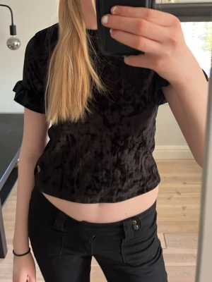 Svart sammetstopp med volang - Säljer denna svart topp i sammet med volang vid ärmen💕Den är i hyfsat bra skick. Vet inte vart den är ifrån. Den är i storlek 146-152💕