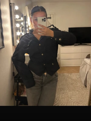 Svart jeansjacka med knappar - Snygg svart jeansjacka med silverfärgade knappar och klassisk krage. Jackan har långa ärmar och två bröstfickor med lock. Köpte den på Sellpy så ja tror inte att den går att få tag i. Den är ifrån clockhouse 